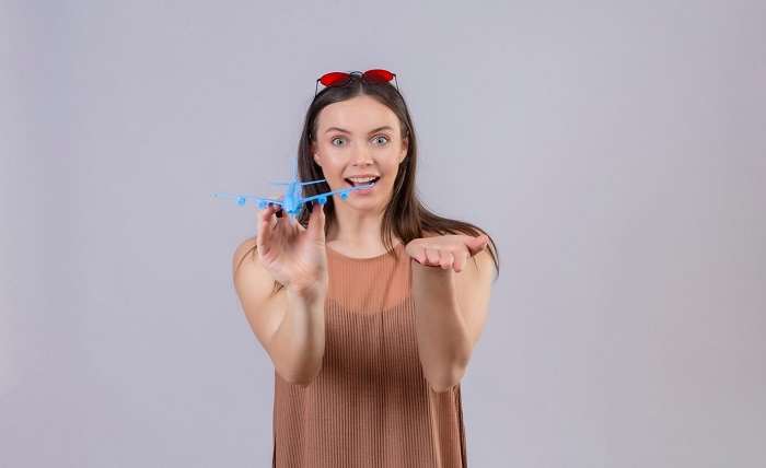 young beautiful woman with red sunglasses head holding toy airplane pointing with arm hand camera smiling with happy face standing white background 141793 24788