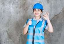 female engineer blue uniform helmet holding blue tea cup showing enjoyment sign 144627 71447