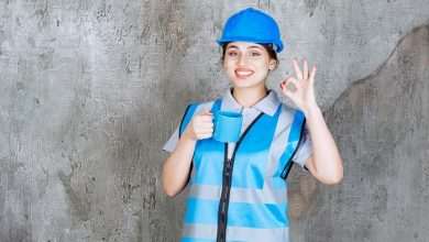 female engineer blue uniform helmet holding blue tea cup showing enjoyment sign 144627 71447